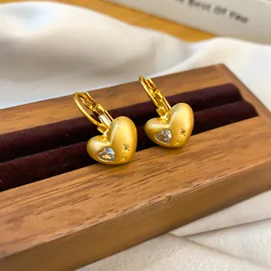 Detailed view of matte gold heart hoop earrings featuring sparkling heart-shaped zircon.