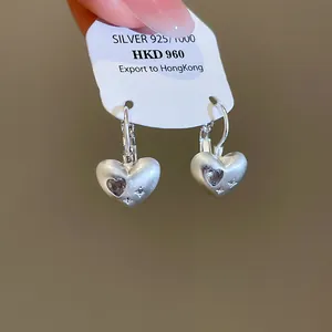 Macro view of matte silver heart-shaped drop earrings with sparkling zircon details