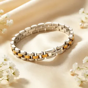 Macro view of a two-tone stainless steel watch band style bracelet on cream silk.