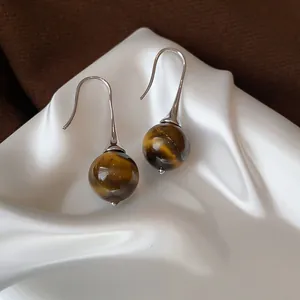 Close-up of vintage tiger eye stone drop earrings with elegant silver hooks