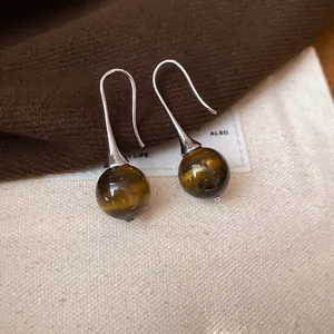 Detailed macro shot of vintage brown tiger eye stone pendant earrings with elegant silver hooks