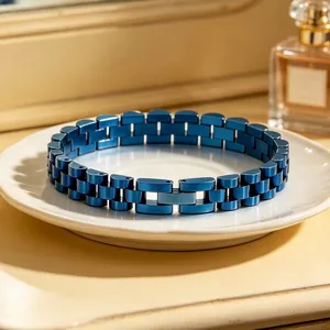 Detailed macro shot of a blue stainless steel watch-link style bracelet on a ceramic plate.