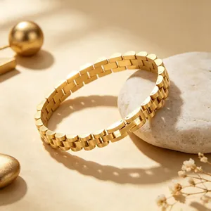Detail shot of a gold-plated stainless steel watchband-style link bracelet on a stone.