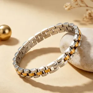 Close-up of a bicolor stainless steel watch-band style bracelet on a stone background