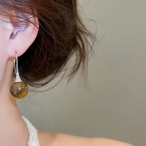 Close-up of a vintage tiger eye drop earring with silver hook worn by a model