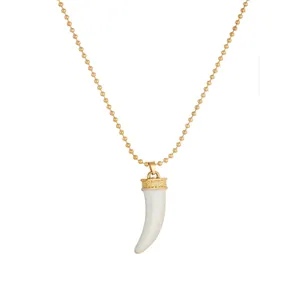 Detail view of ethnic gold-plated ball chain necklace with a white tusk pendant.