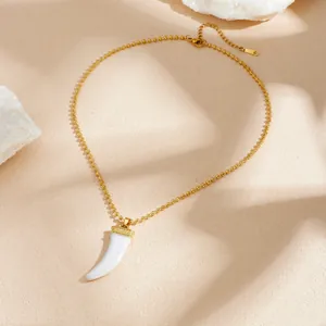 Close-up of ethnic style gold-plated stainless steel necklace with white horn pendant