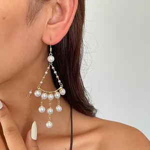Nahaufnahme von eleganten Vintage-Perlenohrringen mit Goldfransen und geometrischem Design.