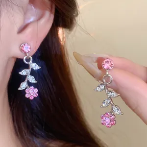 Detailed close-up of pink flower vine earrings with sparkling rhinestones on model