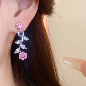 Detailed close-up showing pink floral crystal earrings with leaf design worn on a model