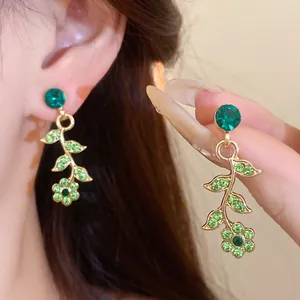 Close-up of elegant green flower rhinestone earrings with a delicate gold-tone vine design
