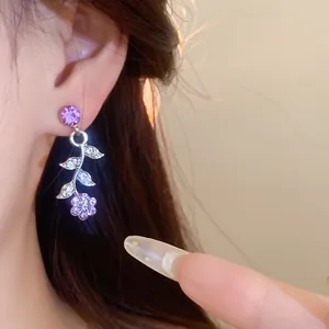 Detailed macro view showing a purple crystal floral branch earring on a model's ear