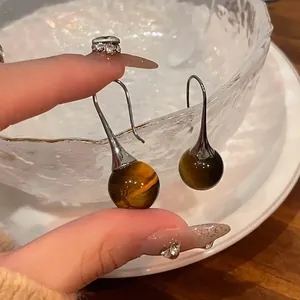 Detailed macro shot of vintage tiger eye stone drop earrings with elegant silver hooks