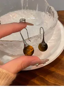 Detail shot of retro Maillard style tiger eye stone bead earrings with silver ear hooks