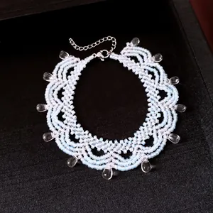 Détail d'un ras-de-cou en dentelle de perles bleu clair avec pendentifs en goutte.