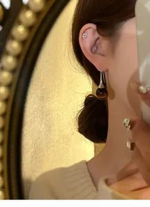 Close-up detail of vintage Maillard style tiger eye stone drop earring on model's ear