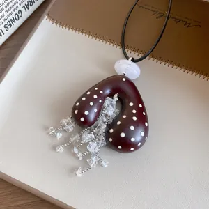 Gedetailleerd macro-zicht op boheemse acryl ketting met stippen, koord en kwastjes