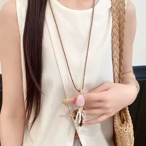 Lange bohemian ketting met roze stenen hanger en veelkleurige kralenkwastjes aan koord