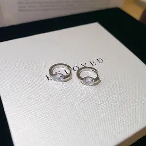 Close-up detail of silver hoop earrings with sparkling round cubic zirconia stone