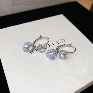 Close-up detail of sparkling multifaceted zircon ball pendant hoop earrings in silver