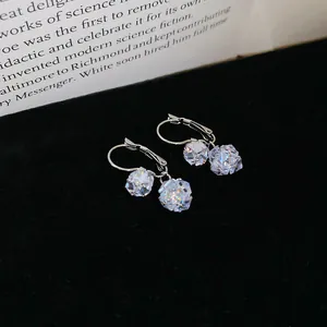 Macro detail of sparkling faceted zirconia pendant earrings on black velvet