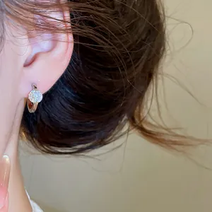 Detailed close-up shot of a sparkling round cubic zirconia solitaire hoop earring on model's ear