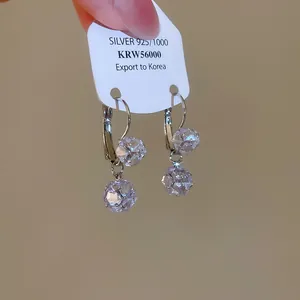 Detailed macro view of sparkling zircon round pendant earrings in silver finish on card
