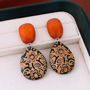 Vue macro détaillée de boucles d'oreilles vintage en bois avec motifs floraux noirs