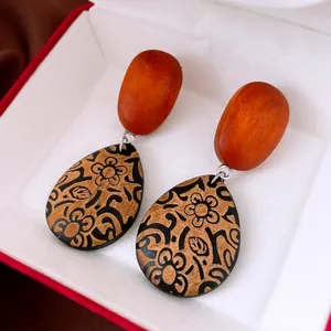 Détail de boucles d'oreilles pendantes en bois style ethnique rétro avec motifs floraux noirs