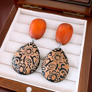 Gros plan de boucles d'oreilles vintage en bois avec imprimé floral dans une boîte