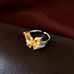 Detailed view of silver-toned open ring featuring yellow and white zircon butterflies