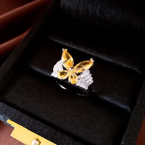 Close-up of a silver-toned butterfly open ring with yellow and clear zircons.