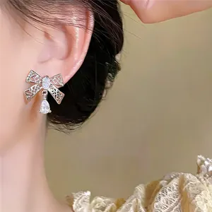 Detailweergave van elegante 18k vergulde zirkoon strik oorbellen aan het modeloor