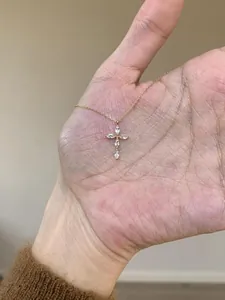 Détail macro d'un délicat collier en chaîne dorée avec un pendentif croix en zircon brillant