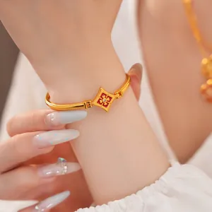 Primo piano di un bracciale vintage placcato oro 24K con fiore in smalto rosso al polso