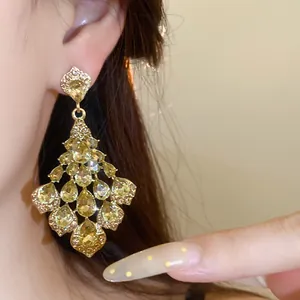 Close-up van vintage gouden kroonluchter oorbellen met champagnegele druppelvormige stenen