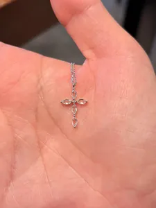 Vue détaillée d'un collier pendentif croix en zircon marquise délicat tenu dans la main
