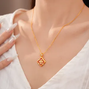 Dettaglio ravvicinato di un ciondolo a fiore placcato oro 24K con smalto rosso e zirconi.