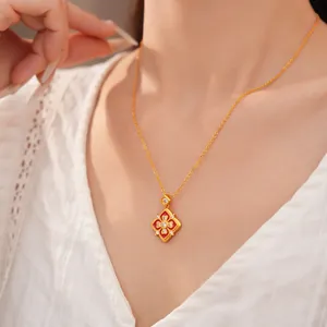Primo piano di una collana a fiore in oro vintage con smalto rosso e zircone su modella