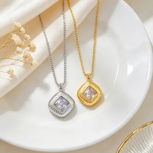 Close-up of square zircon pendants in gold and silver on titanium steel box chains