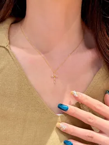 Gros plan d'un collier croix doré élégant avec zircons brillants sur modèle.
