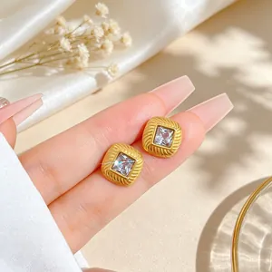 Detailed close-up showing golden square titanium steel earrings with cubic zirconia stone