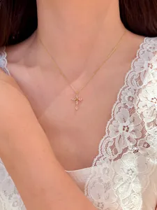 Vue détaillée d'un collier doré fin avec un pendentif croix en zircon brillant