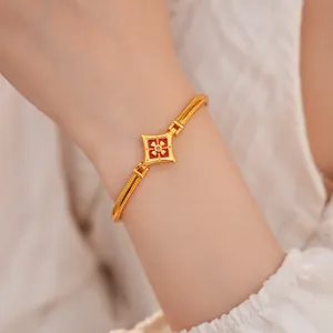 Dettaglio di un bracciale a fiore placcato oro con smalto rosso e zircone sul polso