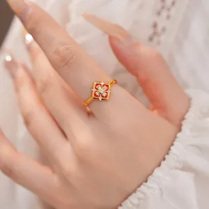 Primo piano di un anello vintage placcato oro con fiore in smalto rosso e zirconi scintillanti.