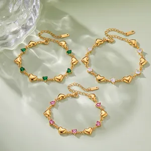 Detaillierte Nahaufnahme von drei goldenen Herzarmbändern mit grünen, weißen und rosa Zirkonia.