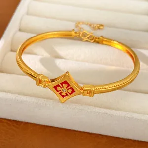 Dettaglio di bracciale rigido placcato oro vintage con fiore smaltato rosso e zircone centrale