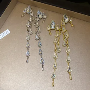 Detailed macro view of long water-drop crystal tassel earrings in gold and silver finishes