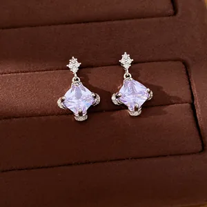 Nahaufnahme eleganter violetter Zirkon-Rhomben-Ohrringe auf einem braunen Samttablett