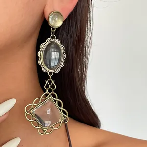 Detailed close-up showing vintage exaggerated metal and resin drop earrings on model
